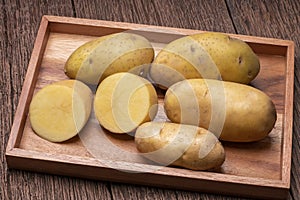 Fresh potatoes and sliced in wooden plate, Table top view Raw potato on a wooden table background.