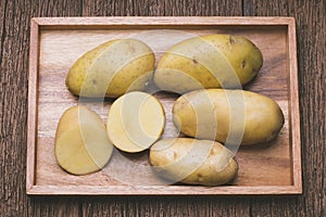 Fresh potatoes and sliced in wooden plate, Table top view Raw potato on a wooden table background.