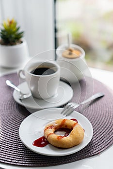 Fresh powdered sugar donuts with chocolate and cup of coffee on wooden table in cafe