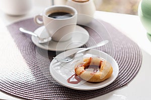 Fresh powdered sugar donuts with chocolate and cup of coffee on wooden table in cafe