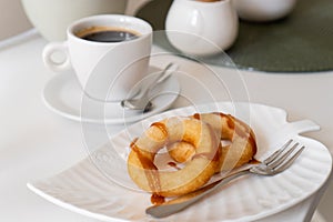 Fresh powdered sugar donuts with chocolate and cup of coffee on wooden table in cafe