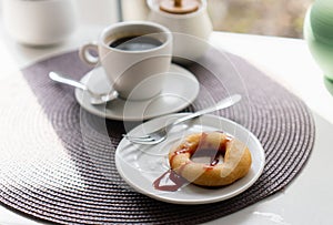 Fresh powdered sugar donuts with chocolate and cup of coffee on wooden table in cafe