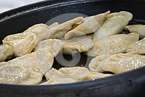 Fresh prepared fried dumplings on frying pan. Traditional polish food