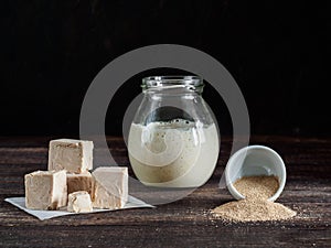 Fresh pressed yeast, dry instant yeast and active wheat sourdough starter on wooden table