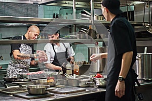 Is it fresh Professional chef in apron holding a red meat and teaching his assistants how to choose it for cooking