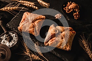 Fresh puff pastry buns on slate background with wheat spikelets and walnut. Pastries and bakery, top view