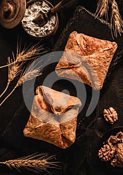 Fresh puff pastry buns on slate background with wheat spikelets and walnut. Pastries and bakery, top view