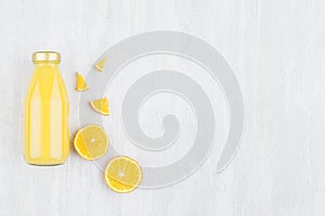 Fresh pulpy yellow orange juice in glass bottle with sliced fruit as mock up for advertising, portfolio, design top view on white.