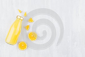 Fresh pulpy yellow orange juice in glass bottle with sliced fruit as mock up for advertising, portfolio, design top view on white.