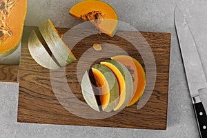 Fresh pumpkin cut into pieces on a wooden cutting board