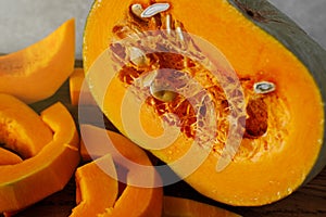 Fresh pumpkin cut into pieces on a wooden cutting board