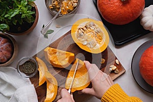 Fresh pumpkin. Cutting pumpkin in slices on cutting board, female hands preparring autumn foods. Baked squash or butternut