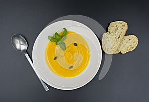 fresh pumpkin soup in plate with black background.