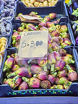Fresh purple Artichokes in a market with a cartel in Italian showing the price
