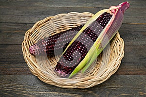 Fresh purple organic corn in basket on wooden table background