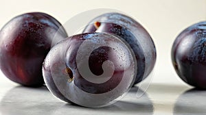 Fresh purple plums with water droplets on reflective surface
