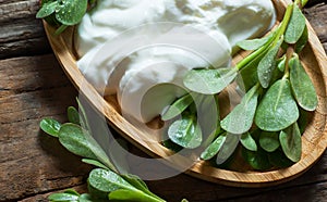 Fresh purslane Portulaca oleracea, edible weeds with yoghurt on wooden table