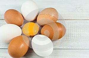 Fresh quail and chicken eggs, egg yolk on white wooden background