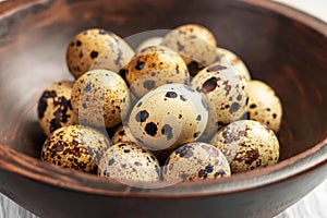 Fresh quail eggs in wooden brown bowl on a board. Easter raw foodstuff
