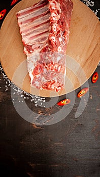 Fresh rack of raw pork spare ribs seasoned with spices on slate tray with leaves at background, Horizontal composition with copy