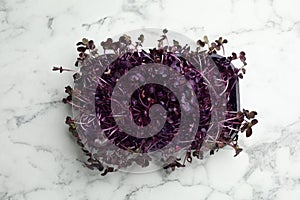 Fresh radish microgreens on white marble table, top view