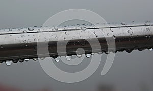 Fresh rain drops on the window steel rod.