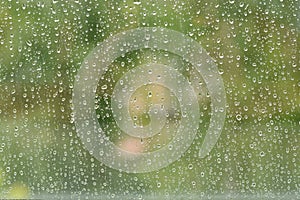 Fresh rain splash drops on a window with background autumn nature