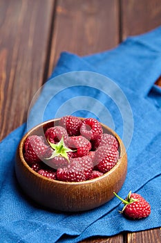 Fresh raspberries in wooden bowl on brown table. Red ripe raspberries, sweet berries