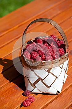 Fresh raspberry in a basket on wooden table