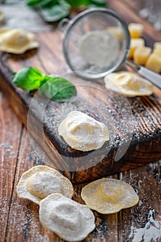 Fresh Ravioli with Parmesan and Basil on a wooden background with flour
