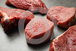 Fresh raw beef cuts on grey table, closeup