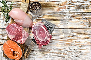 Fresh raw beef striploin steak, chicken breast fillet, pork and salmon steak. White wooden background. Top view. Copy space