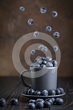 Fresh raw blueberries falling in the air isolated on the yellow background. Food levitation concept. Blueberries in a