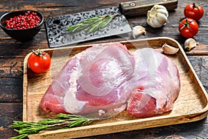 Fresh raw boneless Turkey thigh fillet on a wooden tray. dark background. Top view
