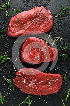 Fresh Raw braising beef steak with herbs on black rustic background photo