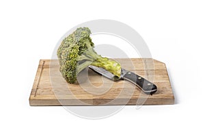 Fresh raw broccoli, cutting board made of wood on a white background. a large knife for cutting in the kitchen