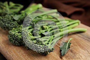 Fresh raw broccolini on wooden board, closeup. Healthy food