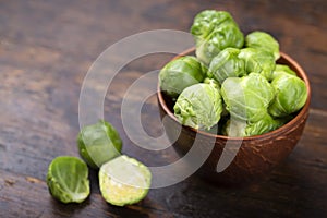 Fresh raw brussels sprouts in a bowl on a wooden table