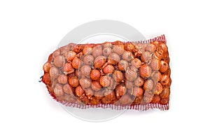 Fresh raw bulbs onion in a red mesh bag on white background. Top view, flat lay