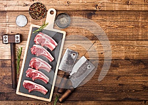 Fresh raw butchers lamb beef cutlets on chopping board with vintage meat hatchets and hammer on wooden background.Salt, pepper and