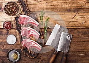 Fresh raw butchers lamb beef cutlets on chopping board with vintage meat hatchets on wooden background.Salt, pepper and oil in