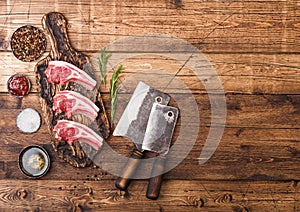 Fresh raw butchers lamb beef cutlets on chopping board with vintage meat hatchets on wooden background.Salt, pepper and oil in