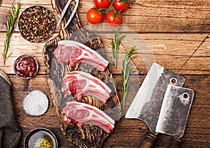 Fresh raw butchers lamb beef cutlets on chopping board with vintage meat hatchets on wooden background.Salt, pepper and oil with