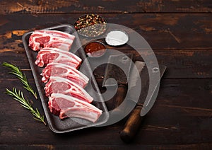 Fresh raw butchers lamb beef cutlets in plastic tray with vintage meat hatchets on wooden background.Salt, pepper and oil in steel