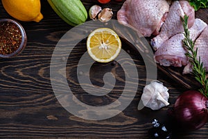 Fresh raw chicken drumstick and thigh on a board with spices and herbs on a wooden table