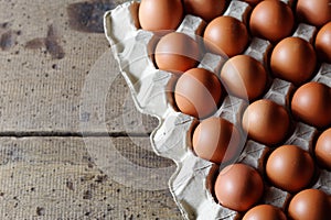 Fresh raw chicken eggs in carton egg box on wooden background
