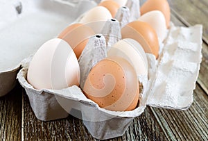 Fresh raw chicken eggs in carton egg box on wooden background.
