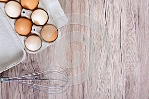 Fresh raw chicken eggs in carton egg box on wooden background.