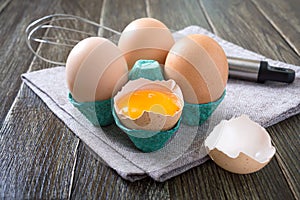 Fresh raw chicken eggs in an cartons egg box. Broken egg, yolk. Organic food for good health high protein on rustic wooden