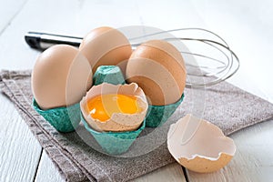 Fresh raw chicken eggs in an cartons egg box. Broken egg, yolk. Organic food for good health high protein on white wooden